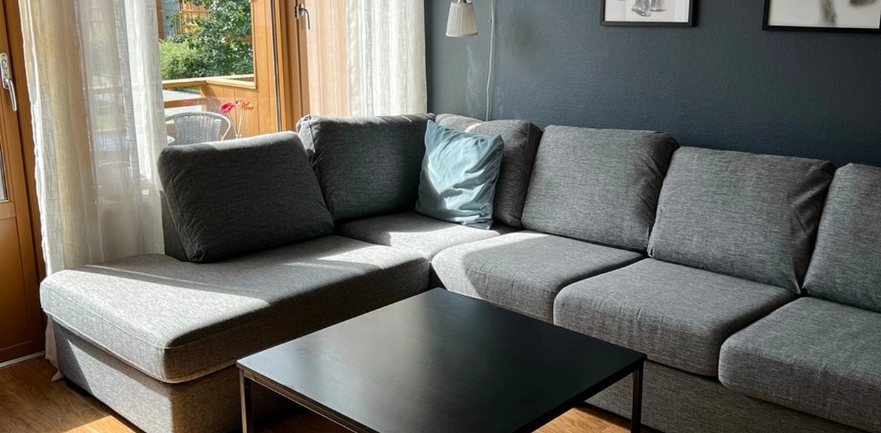 Hyggelig sofakrok med store vindusflater og utgang til balkong.